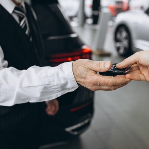 Old man receiving keys from car in a car showroom